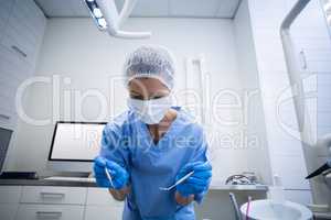 Dental assistant in surgical mask holding dental tools