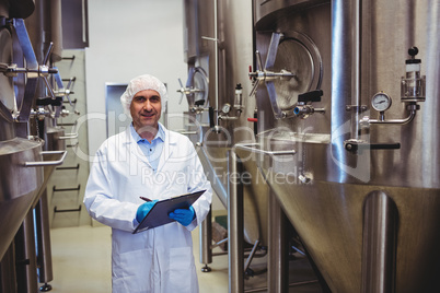 Smiling manufacturer writing while standing at brewery