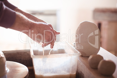 Male potter washing hands after working on pottery wheel