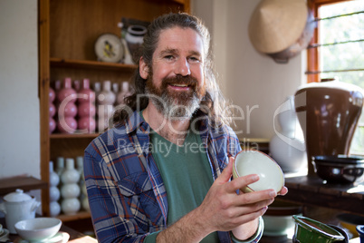 Happy male potter checking bowl