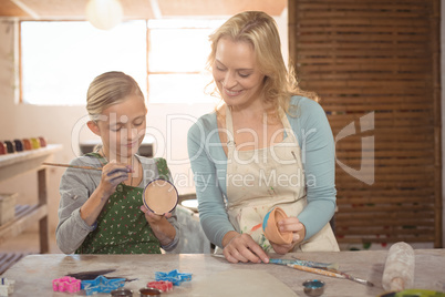 Female potter assisting girl in painting