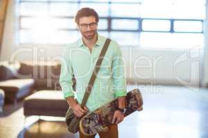 Male business executive standing with skateboard