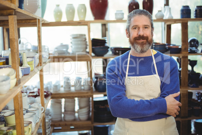 Happy male potter standing in pottery workshop