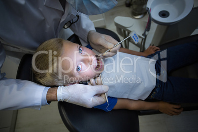 Dentist examining a young patient with tools