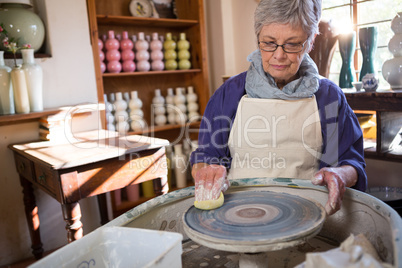 Female potter cleaning pottery wheel
