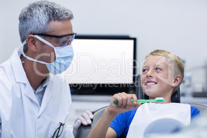 Dentist assisting young patient while brush teeth