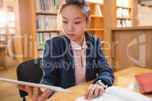 Young woman using digital tablet while studying in library