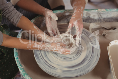 Mid section of female potter assisting girls