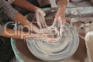 Mid section of female potter assisting girls
