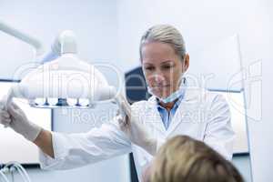 Female dentist adjusting dental light