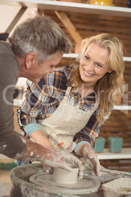 Male potter assisting female potter