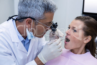 Dentist examining a female patient with dental tools