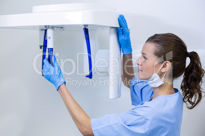 Dental assistant adjusting x-ray equipment