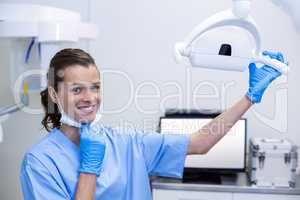 Portrait of dental assistant adjusting light