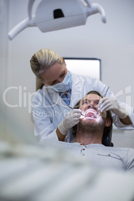 Dentist examining a patient with tools