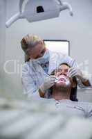 Dentist examining a patient with tools