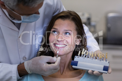 Dentist examining female patient with teeth shades