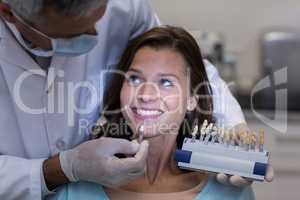 Dentist examining female patient with teeth shades