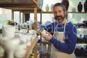 Smiling male potter holding cup in pottery workshop