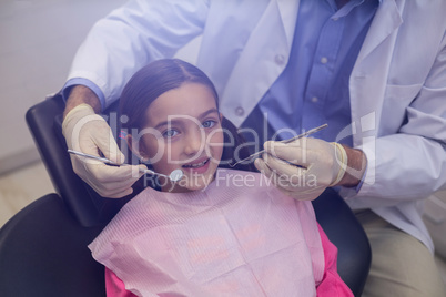 Dentist examining a young patient with tools