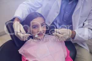 Dentist examining a young patient with tools