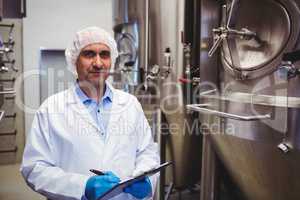 Manufacturer with writing pad standing at brewery