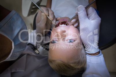 Dentist examining a young patient with tools