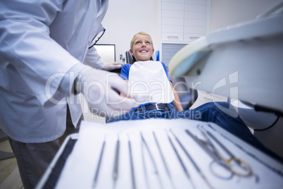 Dentist picking up dental tools to examine a young patient