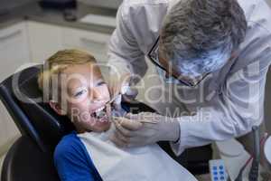 Dentist examining a young patient with tools