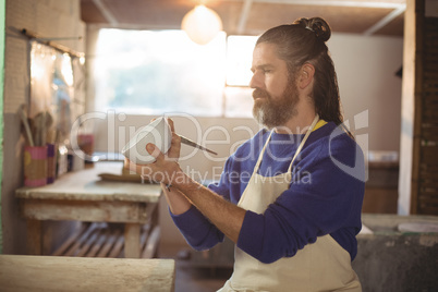 Attentive male potter painting on bowl