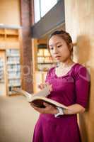 Young woman reading book in library