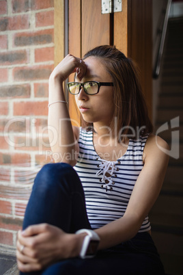 Thoughtful woman sitting on windowsill