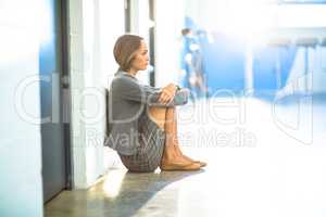 Tired businesswoman sitting on office corridor