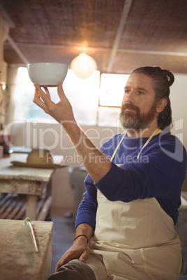 Male potter checking bowl