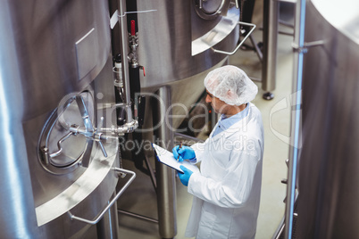 Manufacturer standing amidst storage tanks at brewery