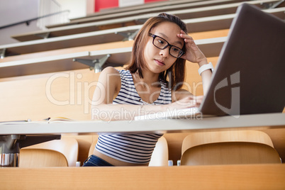 Tensed woman using laptop in classroom