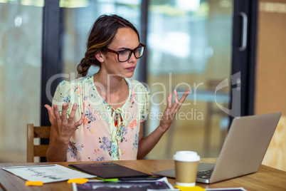 Frustrated female graphic designer looking at laptop