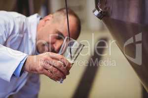 Manufacturer filling beer into glass at brewery