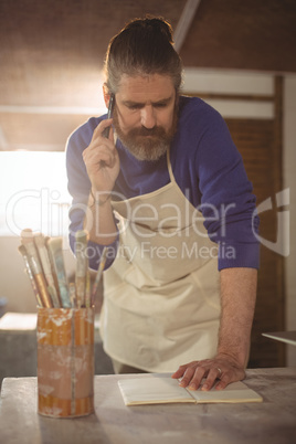 Male potter taking an order on mobile phone