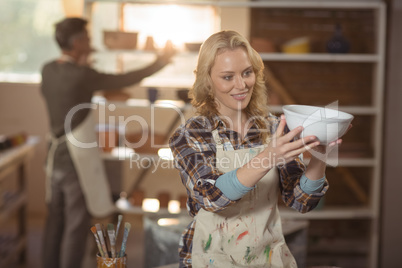 Female potter checking bowl in pottery workshop