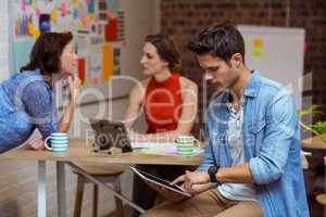 Business executive using digital tablet and colleagues discussin