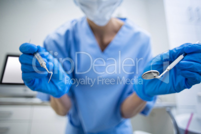 Dental assistant in surgical mask holding dental tools