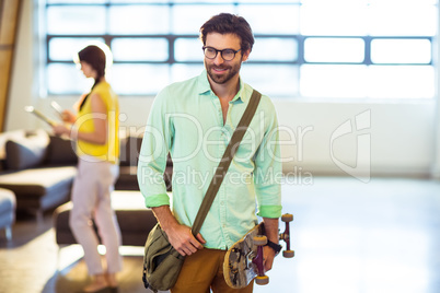 Male business executive standing with skateboard