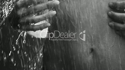 Closeup of woman stomach with touching hands under outdoor shower - black and white video