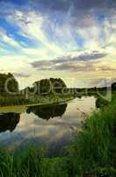 Summer landscape with the sky and clouds reflecting in the river