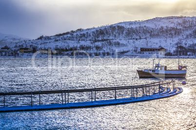 Old wooden boat at a lake surrounded by snow