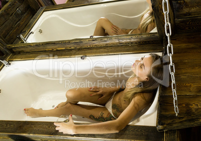 Sexy woman in bathtub holding a glass of white wine