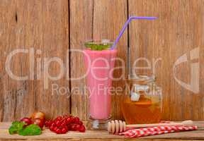 berry smoothie, currants, gooseberries and honey on a wooden sur