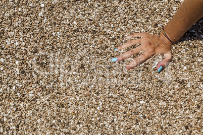 Female hand with cyan nails sinking in the sand