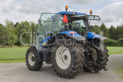 Modern blue tractor on a farmyard.